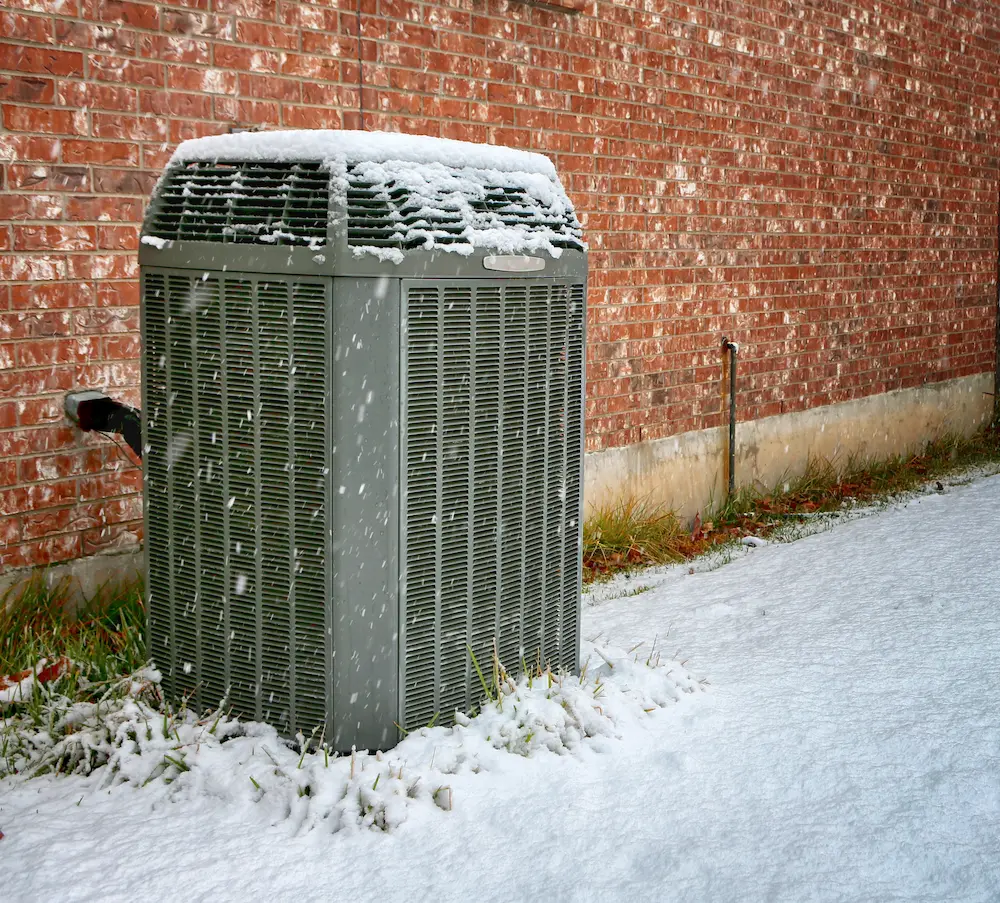 An air conditioner working great outside in the winter snow. 