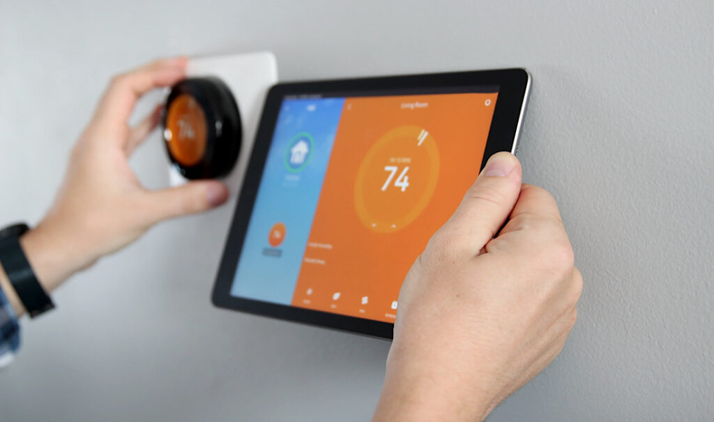 Man is adjusting a temperature using a tablet with smart home app in modern living room in Denver, CO.
